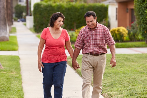 Senior Hispanic Couple Walking Along Sidewalk Together